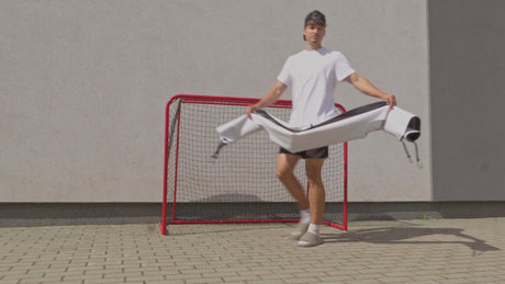 Player holding up the goalie target in front of a floorball goal