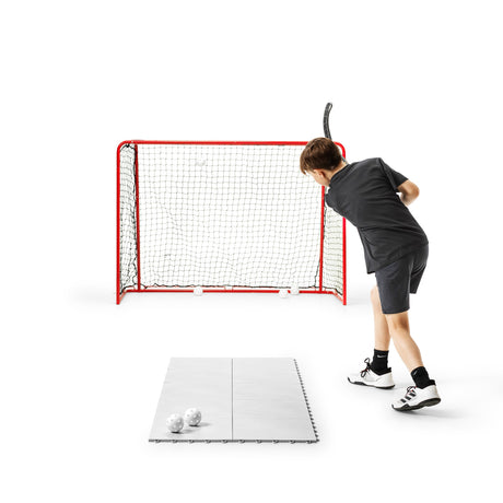 Child shooting floorball at a goal on training tiles during a home confidence session